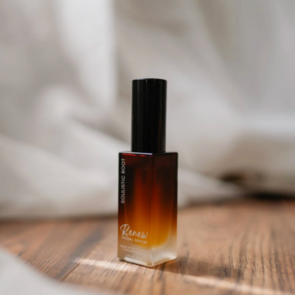 bottle of Facial Serum by Soulistic Root set on a table with white sheet draped in background
